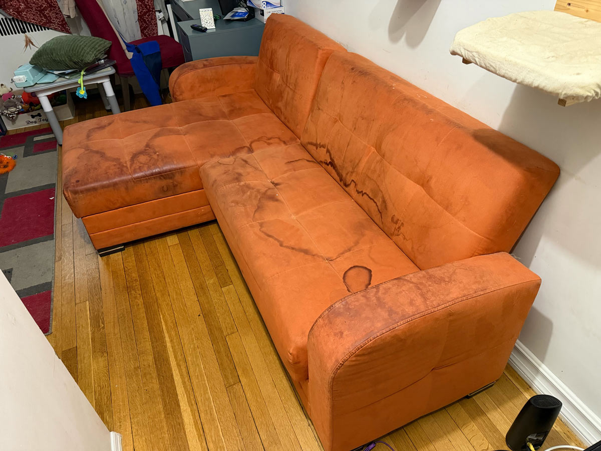 Heavily stained orange microsuede sectional couch before professional cleaning in ZIP 10013 Manhattan